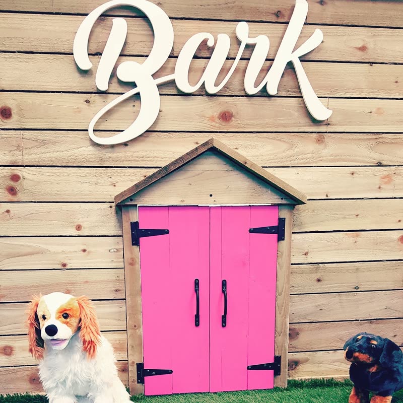 The salon's decorated wall with a kennel playhouse on artificial grass and dog figurines